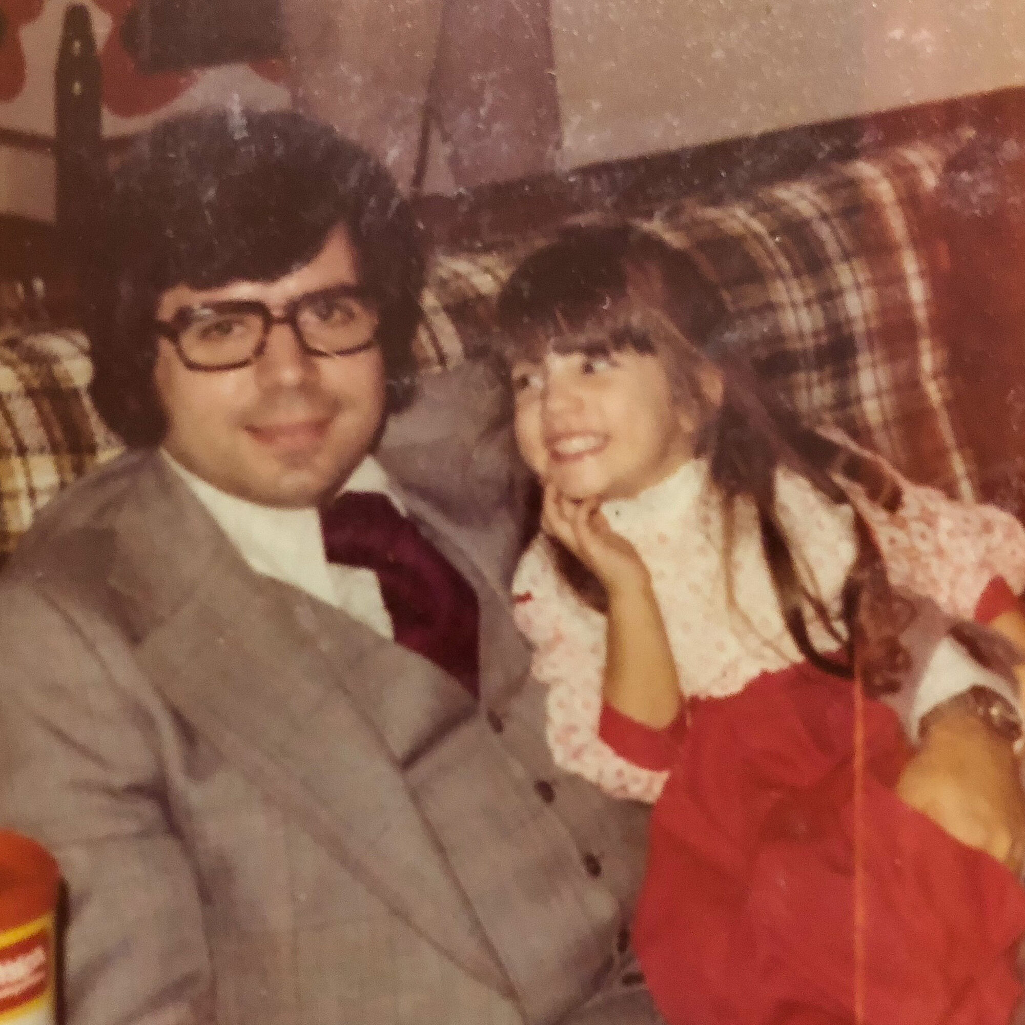Elli Milan as a young girl sitting and smiling on her father's lap