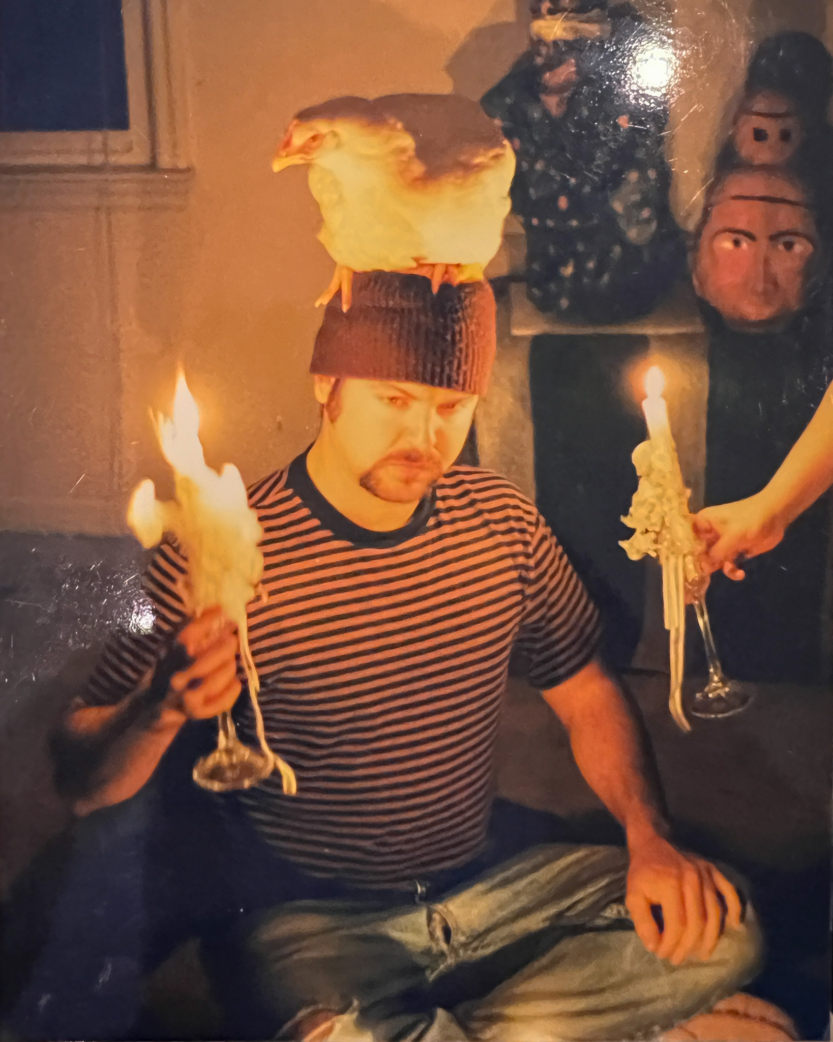 artist john milan poses with a candle, chicken on his head for a creative photoshoot