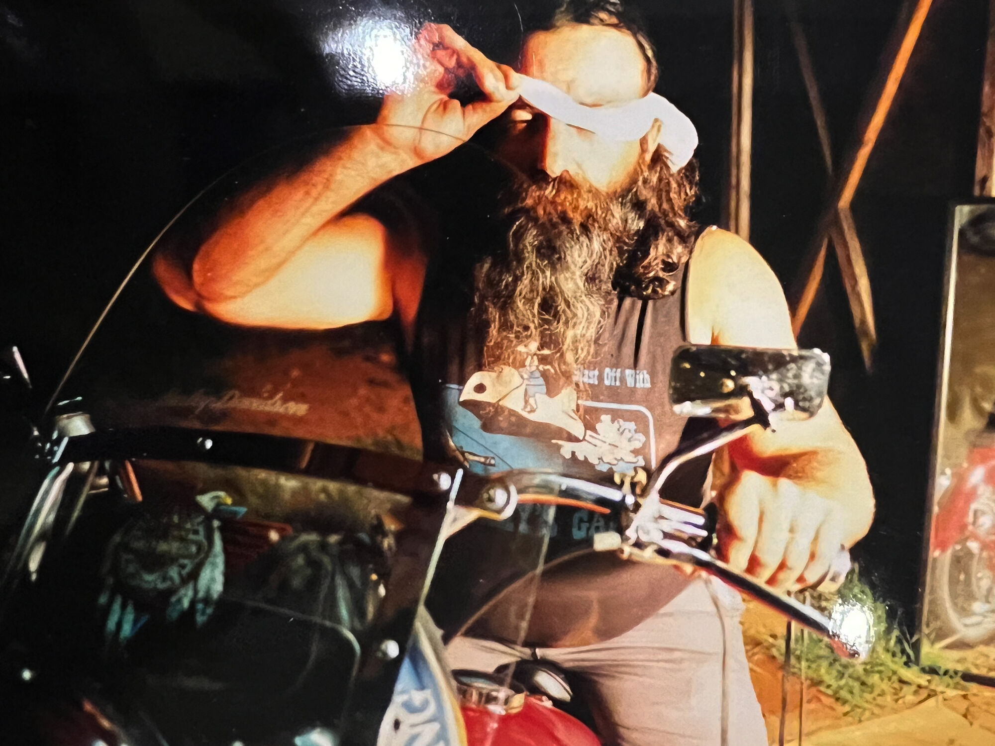 Biker guy with long beard poses on his red motorcycle for a creative photoshoot