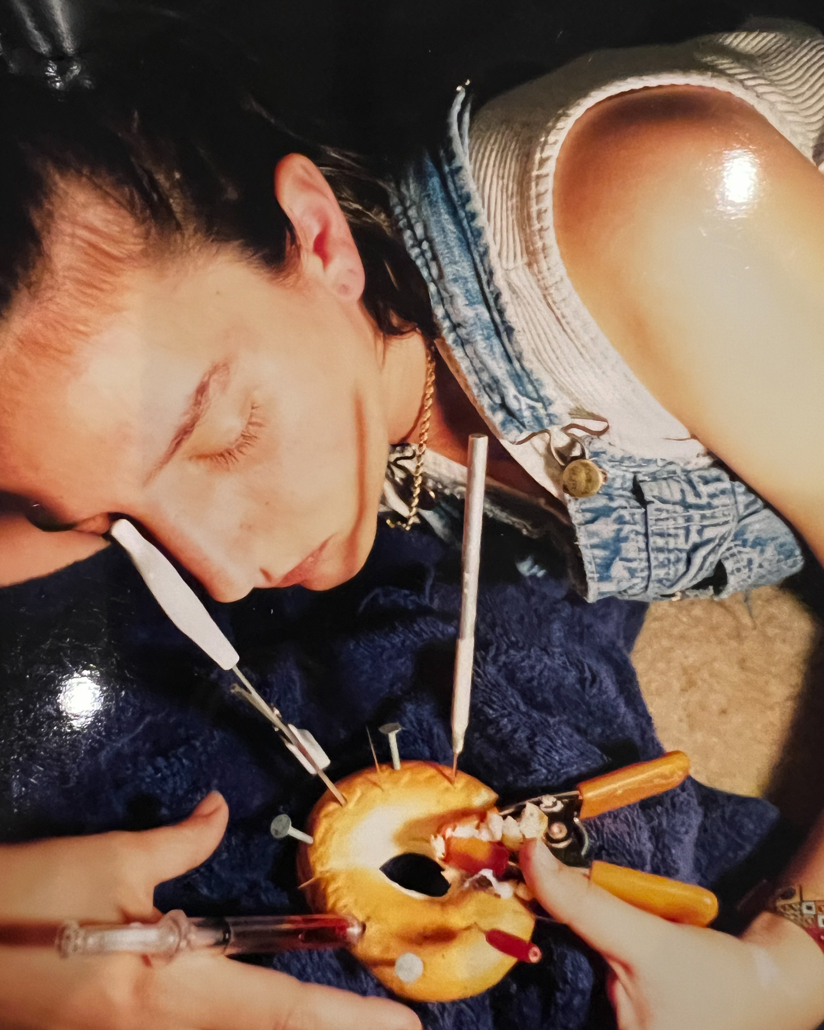 Artist Elil Milan poses with a bagel punctured by nails, needs and clamps