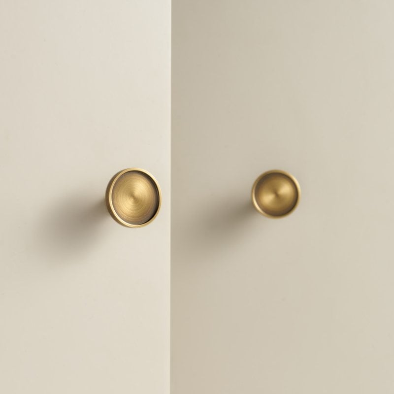 Two RAND dished knobs in satin brass on pale cabinet doors